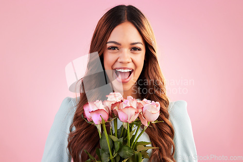 Image of Happy, smile and woman with roses in a studio for valentines day, romance or anniversary. Happiness, excited and portrait of a female model from Mexico with a bouquet of flowers by a pink background.