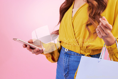 Image of Phone, shopping bag and woman hands isolated on pink background for online shopping, ecommerce and retail. Fashion person on mobile app, cellphone or smartphone for discount, sale or promo in studio