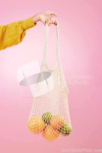 Image of Hand, shopping and bag with fruit in studio by pink background for diet, health and deal in recycle material. Grocery discount, fruits or vegetables from store for food, sustainability and lifestyle