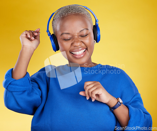 Image of Music, headphones and black woman dance in studio isolated on a yellow background. Podcast, radio and happy African female streaming, enjoying and listening to audio, sound track or song for dancing.