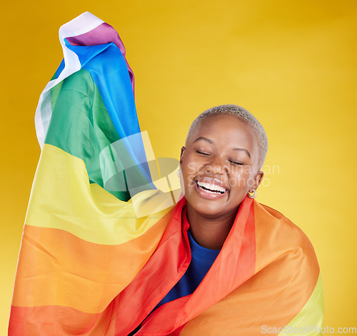 Image of Laughing, lgbtq and black woman with pride flag in studio isolated on a yellow background. Gay, homosexual and lesbian, queer or funny, happy or comic African female with banner for trans or bisexual