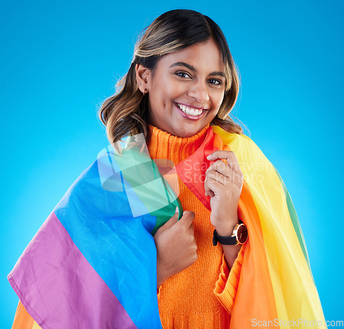 Image of Portrait, pride flag and woman with smile, support and queer against a blue studio background. Face, happy female and lady with equality, symbol for lgbtq community and transgender with human rights