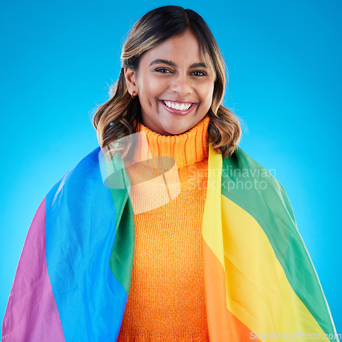 Image of Portrait, pride and woman with rainbow flag, queer and acceptance against a blue studio background. Face, female and happy girl with symbol for lgbtq community, equality and transgender with support