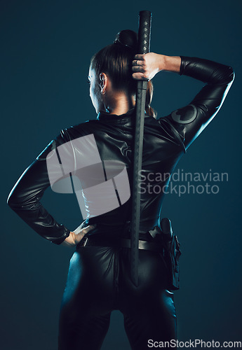 Image of Woman, warrior and back of vigilante with sword in cosplay for battle, war or game against a dark studio background. Rear view of female in black costume with blade for halloween or hunger games