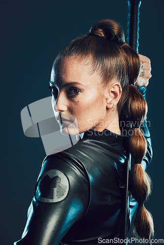 Image of Woman, warrior and vigilante in cosplay with sword ready for battle, war or game against a dark studio background. Portrait of serious female in black superhero costume with blade for halloween