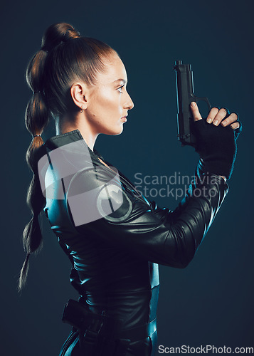 Image of Woman, warrior and gun profile in studio for action, fight and safety from danger. Strong female model, assassin or killer in scifi leather cosplay costume with weapon for action on dark background