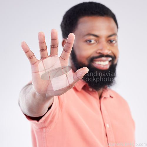 Image of Black man, hand sign and stop in studio portrait with smile, icon and communication by background. Young african model, signal or symbol for opinion, protest palm and warning with confident choice