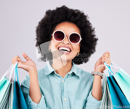 Image of Shopping bag, retail glasses and happy black woman with luxury sales product, designer fashion deal or mall store present. Commerce market, discount gift and studio customer face on gray background