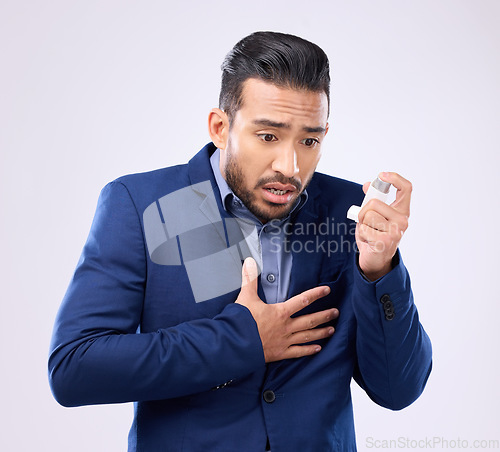 Image of Asthma pump, business man and breathe in studio, medical health and worried of cough in chest pain. Sick male worker breathing medicine inhaler for lungs, oxygen and panic attack of allergy emergency