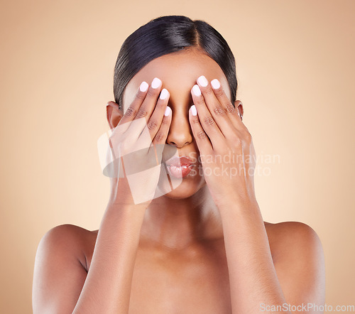 Image of Beauty, pout and woman covering eyes for skincare, self care and cosmetic facial isolated in brown studio background. Dermatology, person and model with hands on face for morning routine