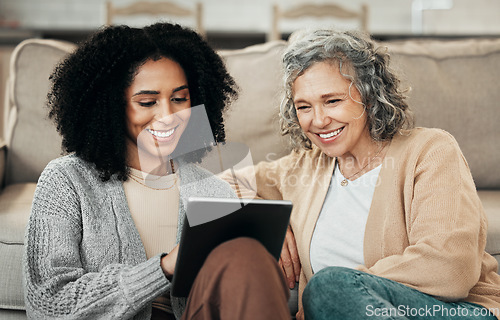 Image of Senior woman, tablet and tech teaching with a mixed race female in a living room showing a app. Family, happiness and home with people watching and streaming a video on technology with a smile