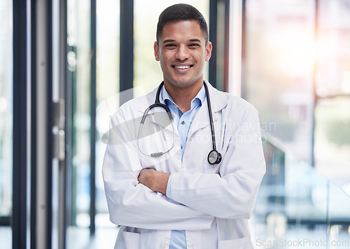 Image of Portrait, man doctor and smile with arms crossed, confidence and professional medicine in hospital. Happy young healthcare worker in lab coat, medical services or expert commitment of pride in clinic