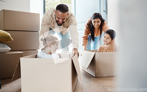 Image of Playful, fun and a family moving into a house, bonding and unpacking their new home together. Happy, game and young parents pushing their children in a box, playing and relocation to an apartment