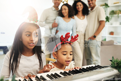 Image of Children, singing and Christmas piano songs on a holiday or vacation excited in a home or house with a happy family. People, celebrate and kids make music or song together in celebration and bonding