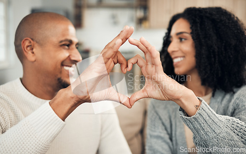 Image of Love, happy and hand heart by couple on sofa with love, care and trust at home together. Emoji, shape and man with woman hands in support of hope, marriage and unity, smile and joy in living room