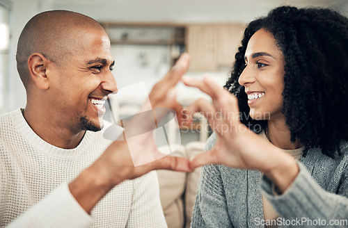 Image of Happy, love and hand heart by couple on sofa with love, care and trust at home together. Emoji, shape and man with woman hands in support of hope, marriage and unity, smile and joy in living room