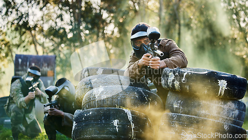 Image of Team, paintball and tires for cover bunker or protection while firing or aiming down sights together in nature. Group of people waiting in teamwork for opportunity to attack or shoot in extreme sport