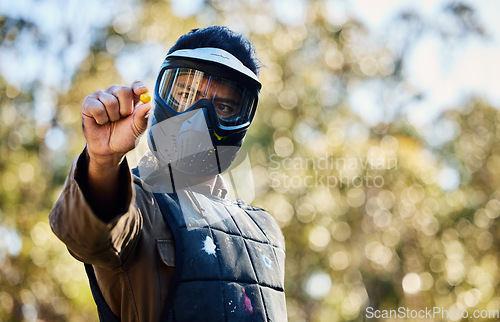 Image of Man, paintball and hands holding ball on the battlefield for war, shot or engaging act in nature. Male paintballer or soldier showing or pinching paint bullet in military or extreme adrenaline sports