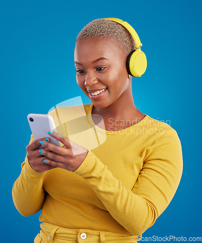 Image of Happy, phone and music with black woman in studio for streaming, multimedia and browsing. Search, smile and audio with female and headphones on blue background for listening, online radio and songs