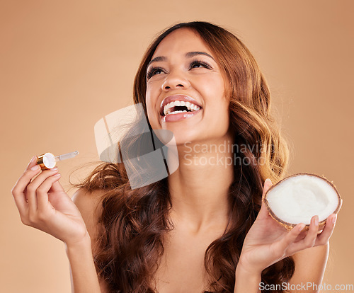 Image of Woman, hair and oil serum and coconut, beauty with cosmetic product and organic on studio background. Balayage, haircare treatment with pipette , cosmetology and female smile and natural cosmetics