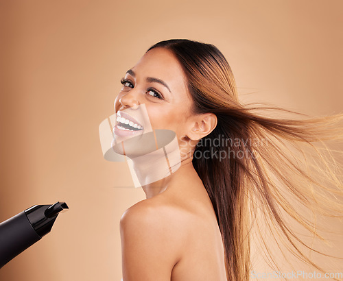 Image of Woman, beauty and hair care portrait with hairdryer and growth or shine for strong texture on brown background. Aesthetic female happy in studio with blow dryer and heat protect for health and color