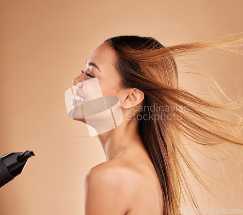 Image of Hairdryer, beauty and hair care with a woman in studio for growth or shine with strong texture. Aesthetic female laugh on brown background with blow dryer and heat protect for healthy color profile