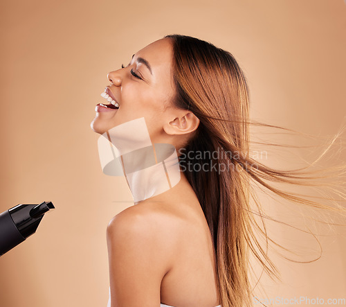 Image of Beauty, woman and hair care with hairdryer in studio for growth or shine with strong texture. Happy aesthetic female laugh using blow dryer and heat protect for health and color on a brown background