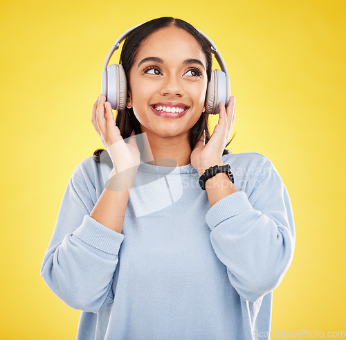 Image of Happy, music and headphones with woman in studio for streaming, online radio and audio. Smile, media and podcast with female isolated on yellow background for technology, listening and connection