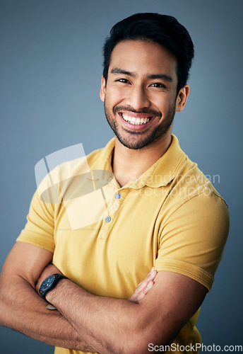 Image of Portrait, smile and Asian man with arms crossed, confidence and relax on a blue studio background. Face, Japanese male and guy with leadership, casual fashion outfit and success with joy and cheerful