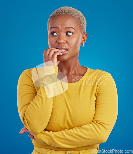 Image of Nervous, worried and scared black woman in fear and bitting nails isolated against a studio blue background. Mental health, anxiety and anxious female in terror feeling confused, problem and crisis