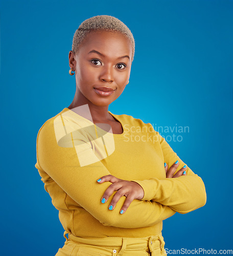 Image of Portrait, fashion and arms crossed with a black woman on a blue background in studio feeling confident. Serious, focus or empowerment and an attractive young female looking proud with confidence