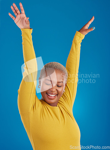 Image of Black woman, happy and freedom celebration in studio with a smile of a winner with hands raised. African female celebrate freedom, energy dance and mindset winning prize or lottery on blue background