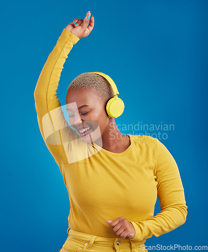 Image of Black woman with headphones, dancing and listening to music, rhythm and fun with freedom on blue background. Happy female with yellow aesthetic, streaming radio with dance and carefree in studio