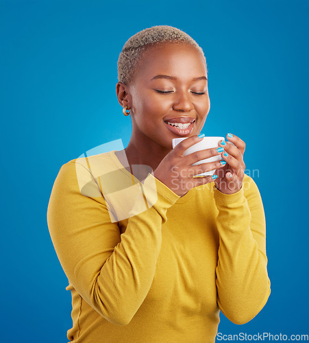 Image of Black woman, happy and coffee or tea smell in studio with a smile and happiness. African female model with a drink and hands on cup to relax with a positive mindset on blue background with beauty