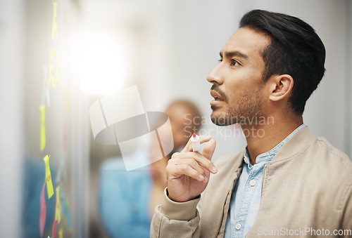 Image of Asian man, thinking and planning business schedule for project, tasks or brainstorming at the office. Thoughtful creative male with marker for idea strategy, decision or sticky note plan on board