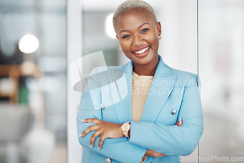 Image of Black woman, portrait smile and arms crossed in small business management leaning on glass in modern office. Happy African American female smiling in confidence for corporate success at the workplace