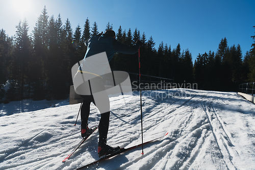 Image of Nordic skiing or Cross-country skiing classic technique practiced by man in a beautiful panoramic trail at morning.