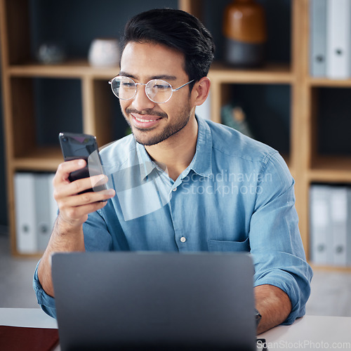 Image of Happy asian man, phone and laptop for social media, communication or networking at office desk. Male creative designer smiling with smartphone by computer for browsing, research or planning startup