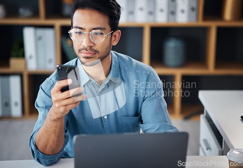 Image of Phone, serious and businessman texting on mobile app in company office as internet or online communication. Laptop, cellphone and man employee startup entrepreneur networking or searching the web