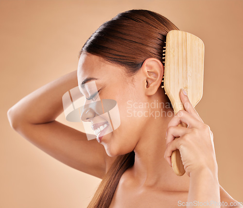 Image of Woman, beauty and hair brush for healthy growth and shine or texture on a brown background. Smile of aesthetic female happy in studio brushing for natural keratin treatment haircare results profile