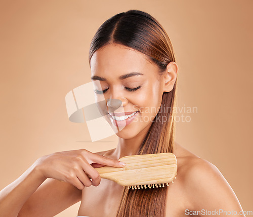 Image of Woman, beauty and brushing hair for growth and shine for healthy texture on a brown background. Smile of aesthetic female happy in studio with a brush for natural keratin treatment haircare results