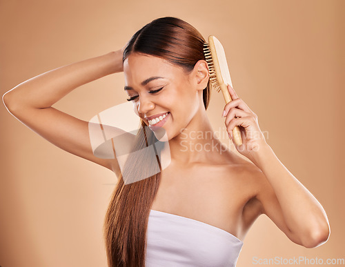 Image of Smile, beauty and woman brushing hair for growth and shine for healthy texture on brown background. Aesthetic female model happy in studio with a brush for natural keratin treatment haircare results