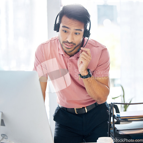 Image of Serious asian man, call center and computer in customer service or desktop support at office desk. Male consultant agent standing by PC in telemarketing advice or insurance with headset at workplace