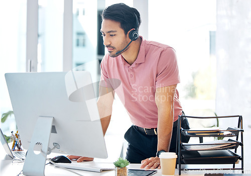 Image of Serious asian man, call center and computer in customer service or desktop support at office desk. Male consultant agent standing by PC in telemarketing advice or decision with headset at workplace