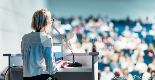 Image of Female speaker giving a talk on corporate business conference. Unrecognizable people in audience at conference hall. Business and Entrepreneurship event.