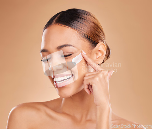 Image of Funny, face skincare and woman with cream in studio isolated on a brown background. Dermatology, beauty cosmetics and happy female model apply lotion, creme or facial moisturizer for skin health.