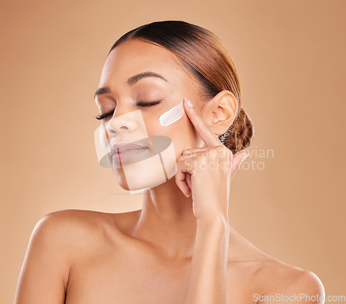 Image of Face, beauty skincare and woman with cream in studio isolated on a brown background. Dermatology, cosmetics and mixed race female model with lotion, creme or facial moisturizer product of skin health
