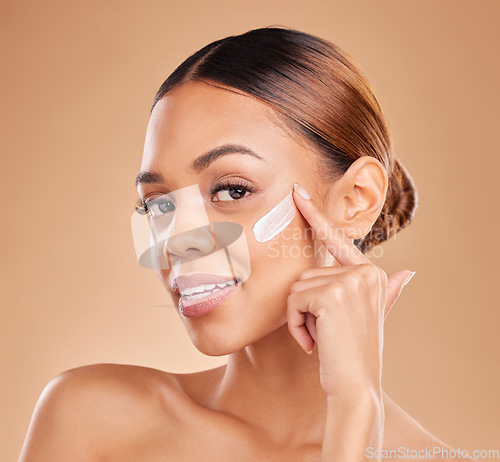 Image of Face, skincare portrait and woman with cream in studio isolated on a brown background. Dermatology, beauty cosmetics and happy female model apply lotion, creme or facial moisturizer for skin health.