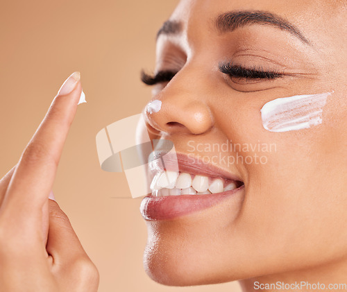 Image of Face, skincare smile and woman with cream in studio isolated on a brown background. Dermatology, beauty cosmetics and closeup of happy female model with lotion, creme or moisturizer for skin health.