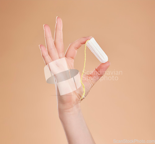 Image of Menstruation, showing and hand with a tampon isolated on a studio background. Healthcare, gynecology and woman holding a feminine product for bleeding, menstrual cycle and protection during period